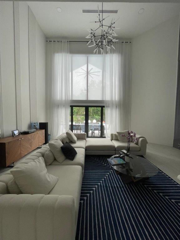A living room with white furniture and a blue rug