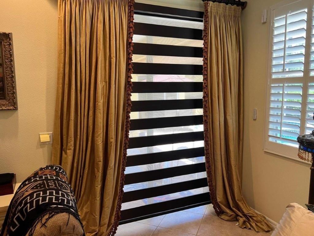 A bedroom with striped curtains and shutters on the windows.