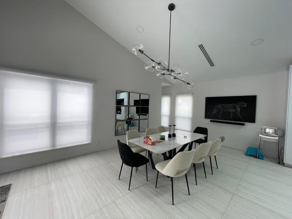 A dining room with a table and chairs and a chandelier hanging from the ceiling.