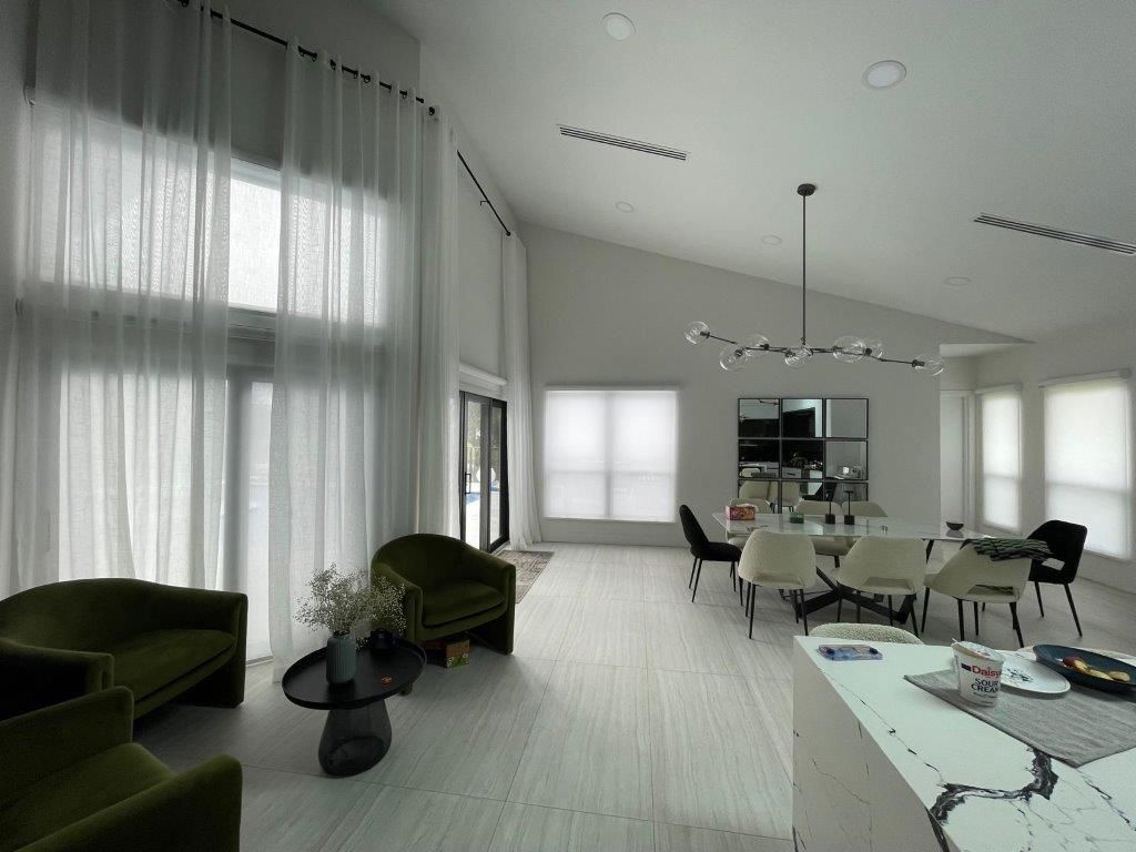 A living room with a dining room and a kitchen in the background