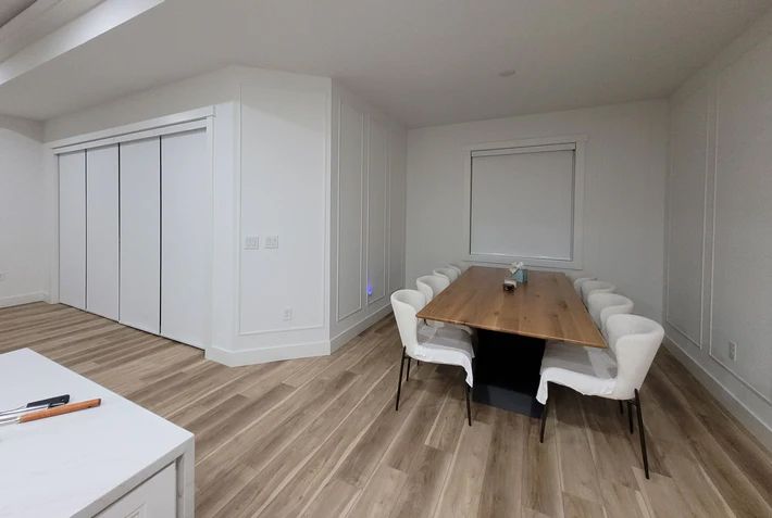 A dining room with a wooden table and white chairs.