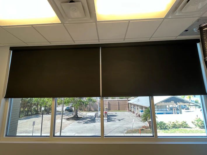 A window with black blinds and a view of a parking lot