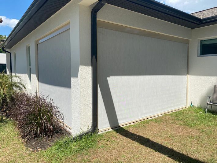 A white house with a screen on the side of it.