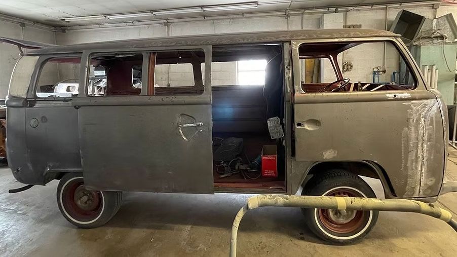 Grey vintage Volkswagen van in a repair shop with door open.
