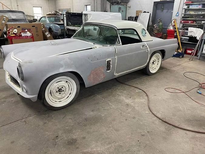 Classic gray Ford Thunderbird hardtop in a workshop, undergoing restoration.