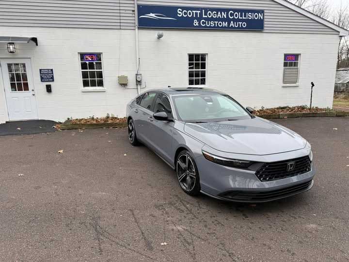 Gray sedan parked in front of a collision repair shop.