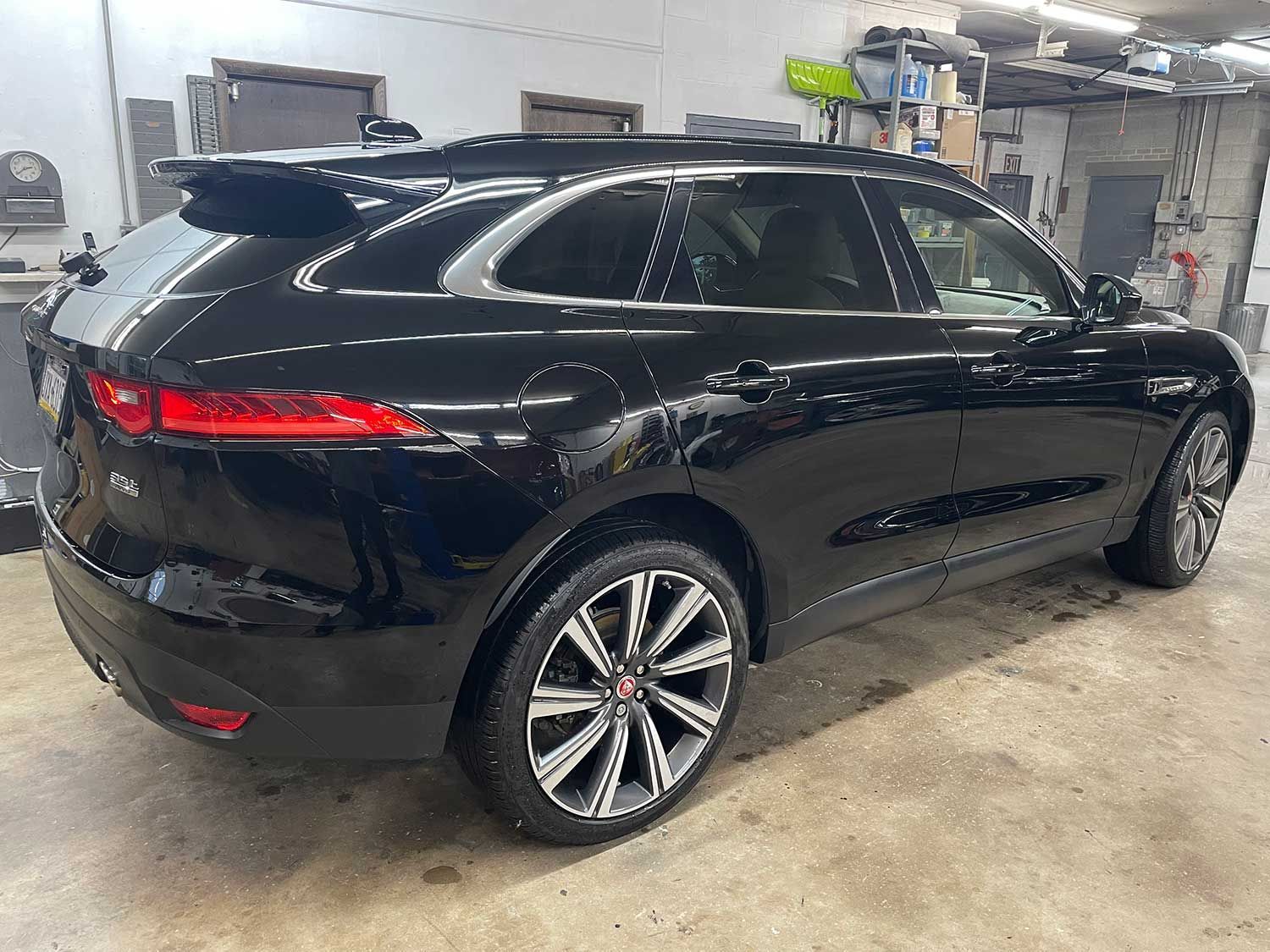 Black Jaguar F-Pace SUV parked inside a garage. The car has silver rims and is angled towards the right.