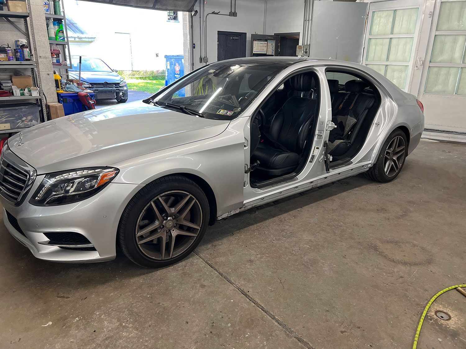 Silver Mercedes sedan in a garage with open doors.