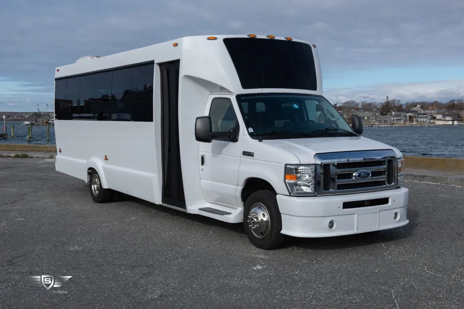 White passenger bus parked on asphalt near water.