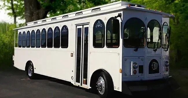 White trolley bus with arched windows, parked outdoors.