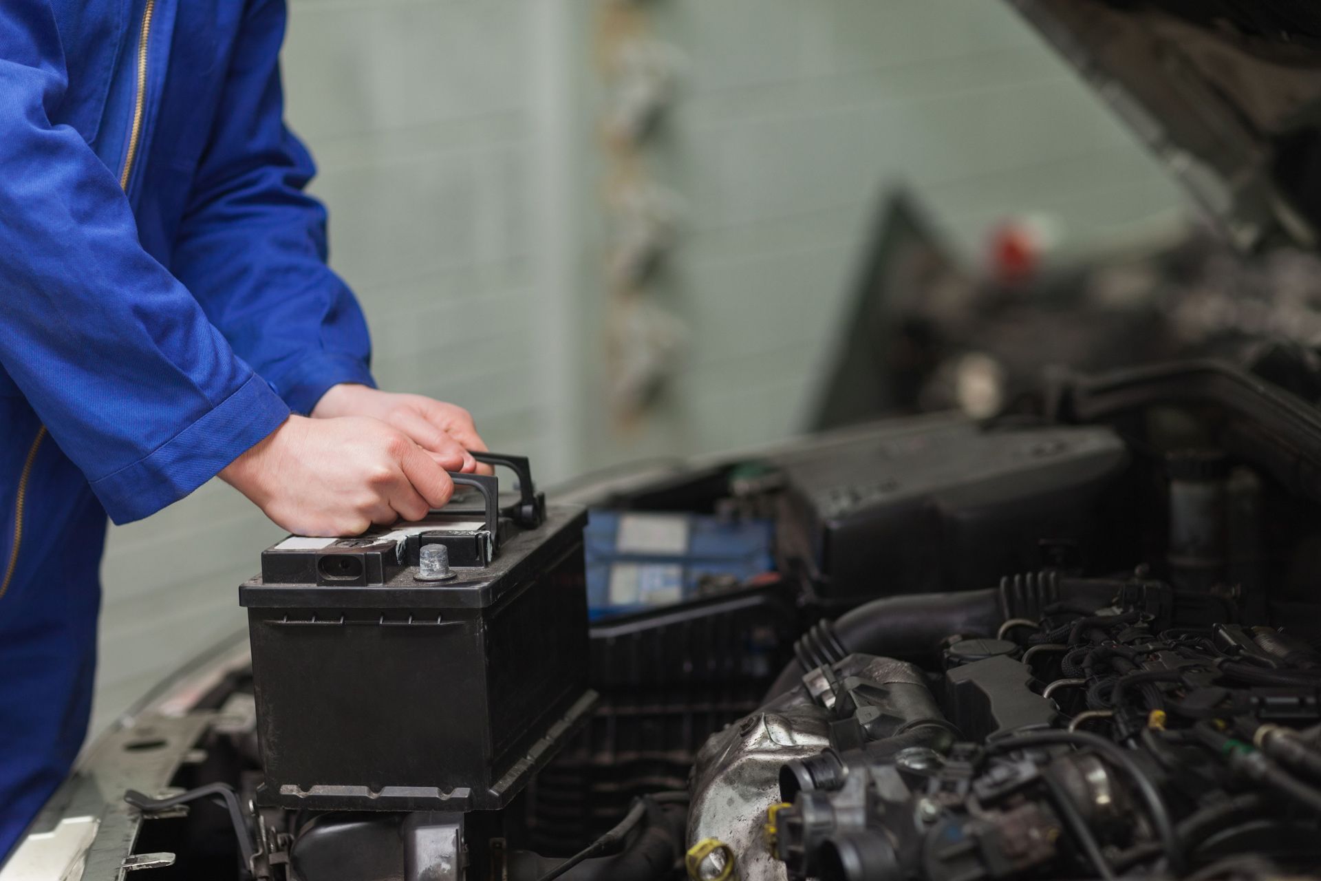 a mechanic is changing a car battery in a garage