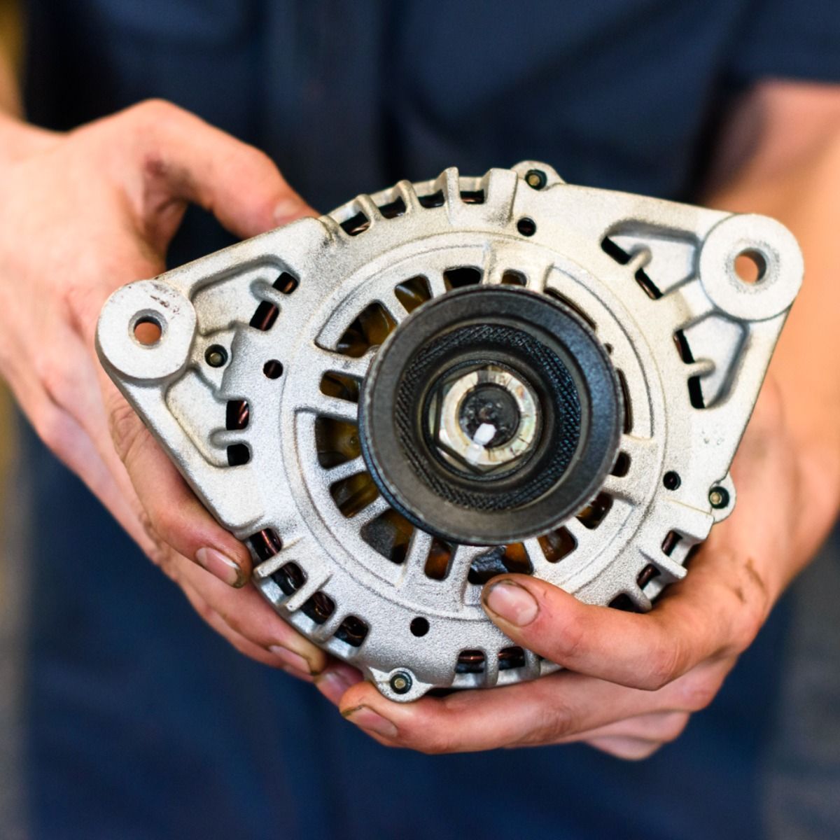 a person is holding a car alternator in their hands