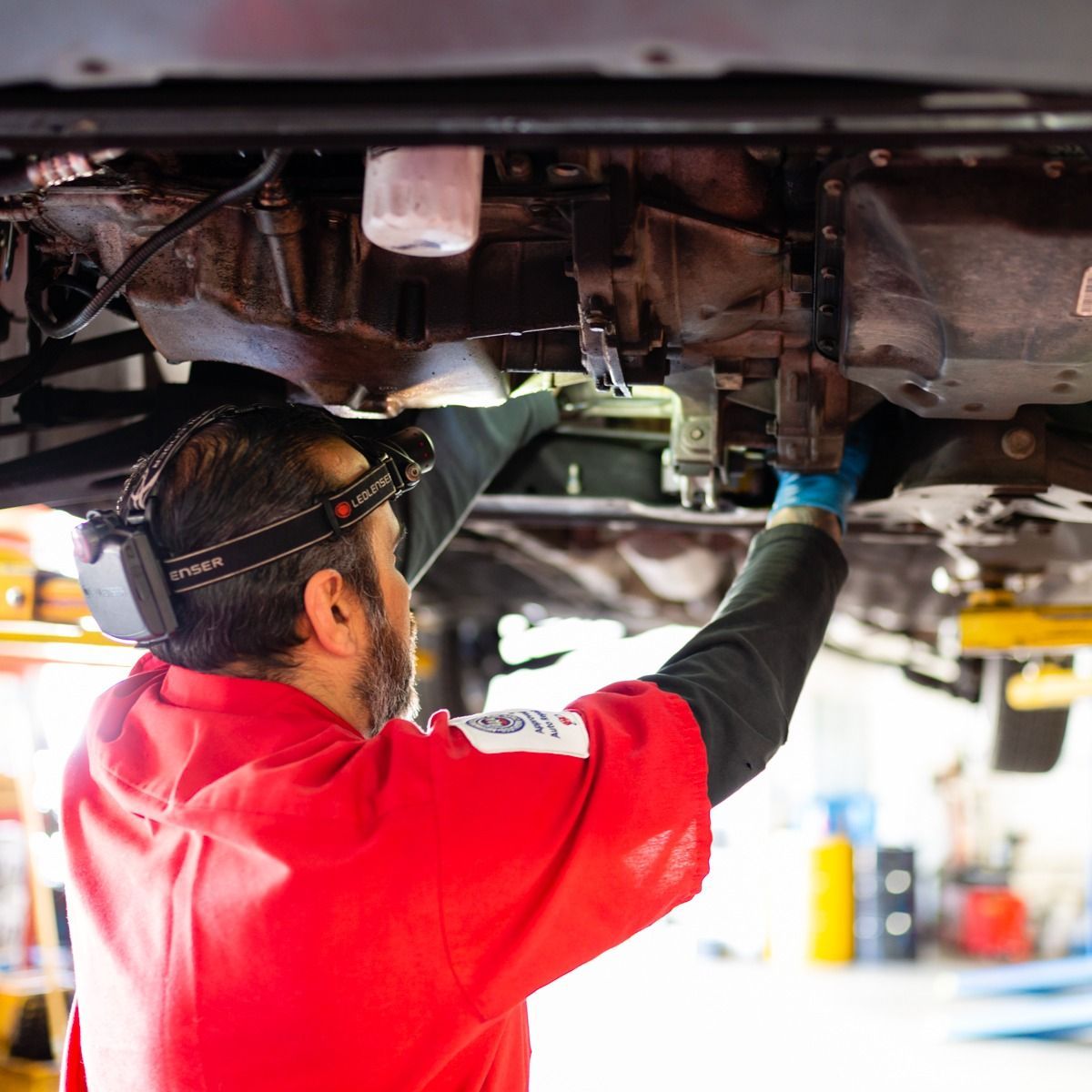 a man in a red shirt is working under a car