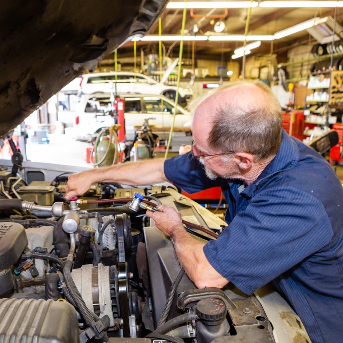 a man in a blue shirt is working on a car engine