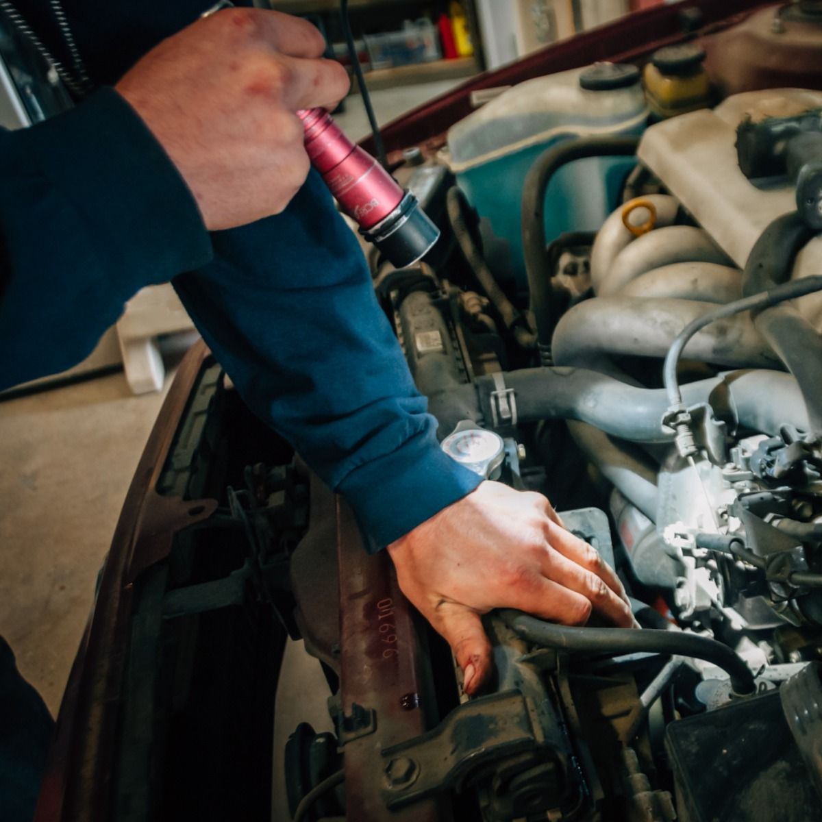 a man is working on a car engine with a flashlight