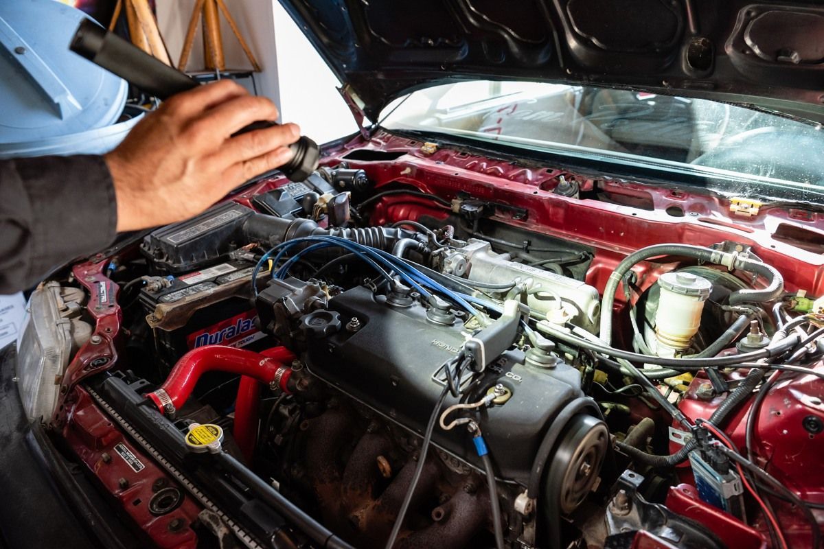 a man is working on the engine of a red car