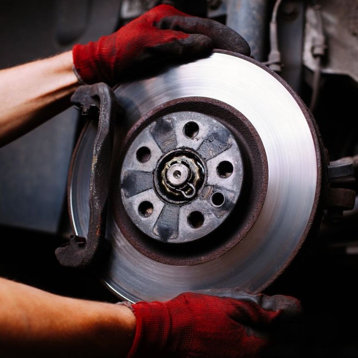 a person wearing red gloves is working on a brake disc