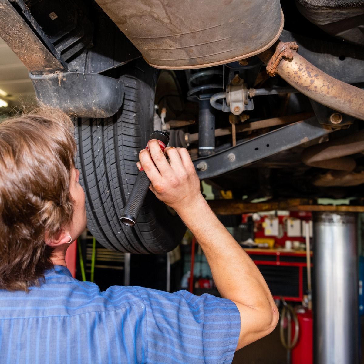 a man is working on the underside of a car in a garage