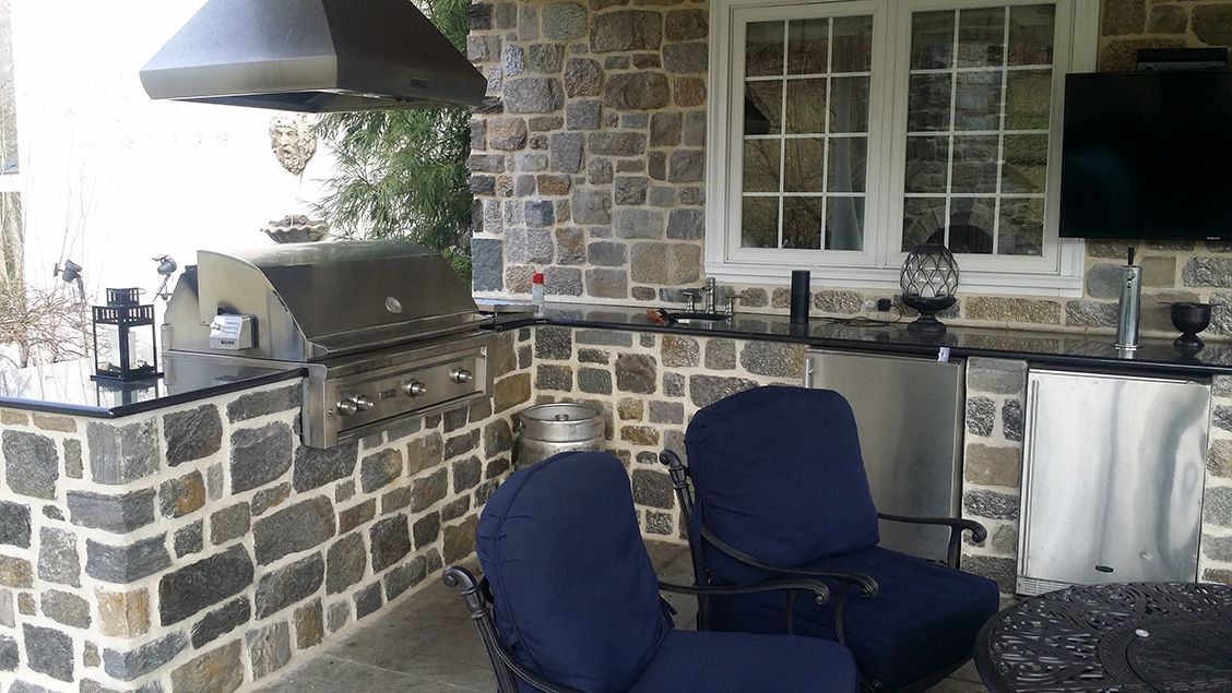 A kitchen with a grill , chairs , a table and a television.