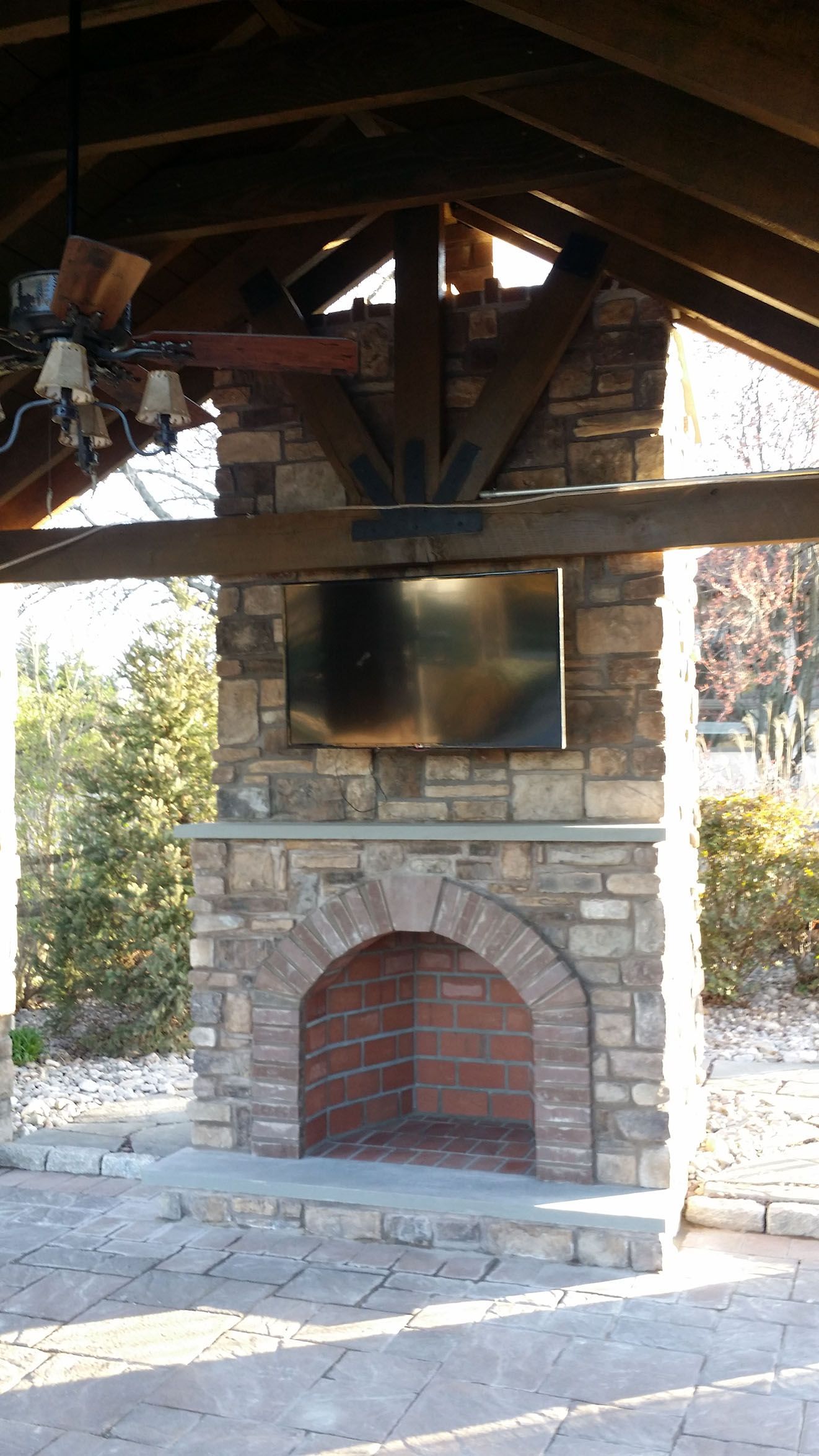 A stone fireplace is under a wooden roof.
