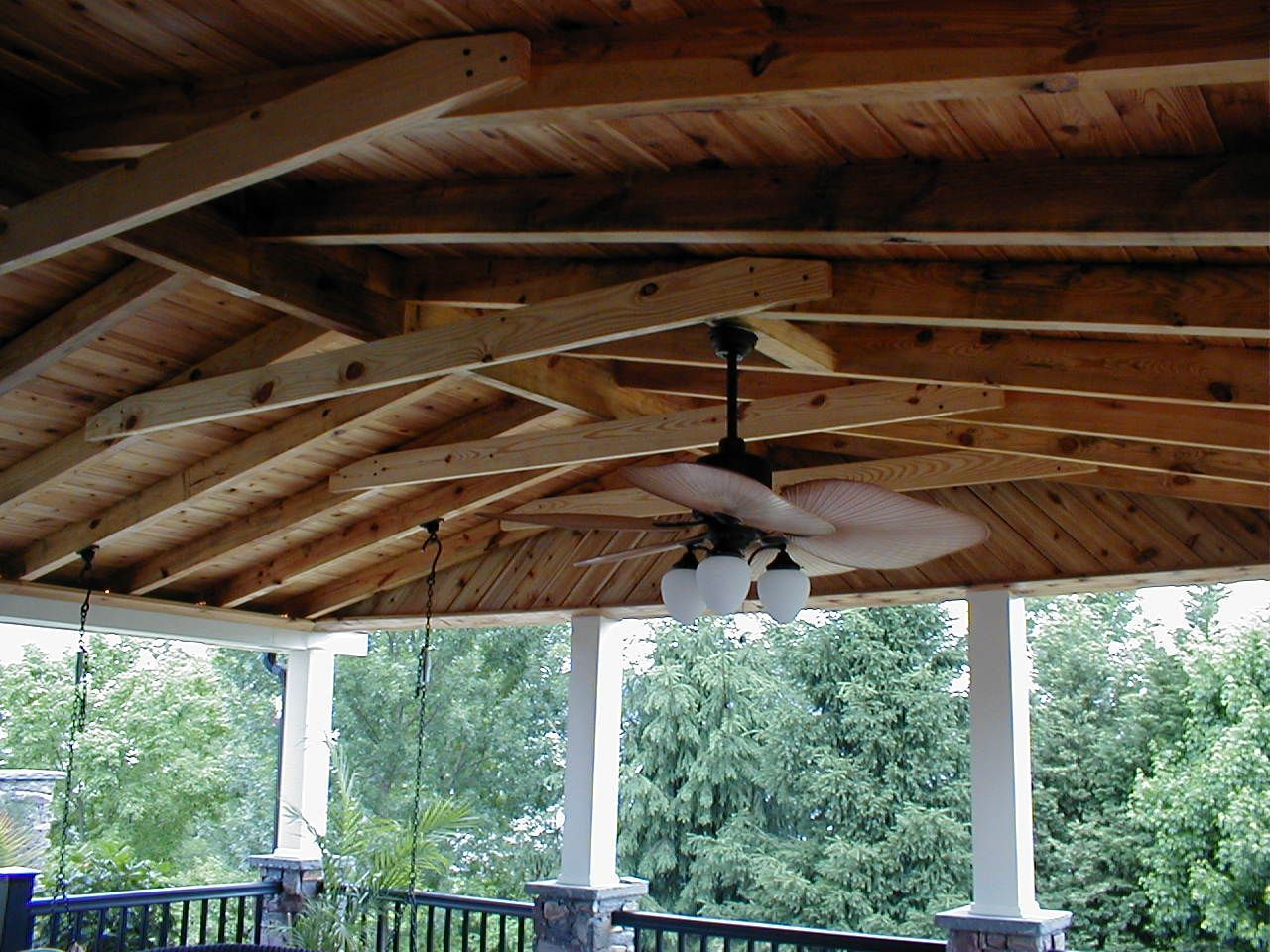 A wooden porch with a ceiling fan hanging from it