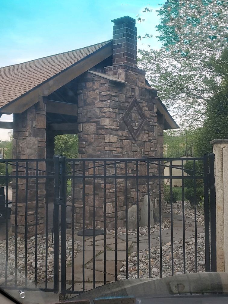 A stone building with a chimney is behind a metal fence