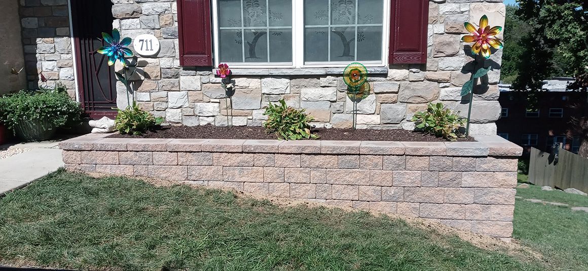 A stone wall with a planter in front of a house.