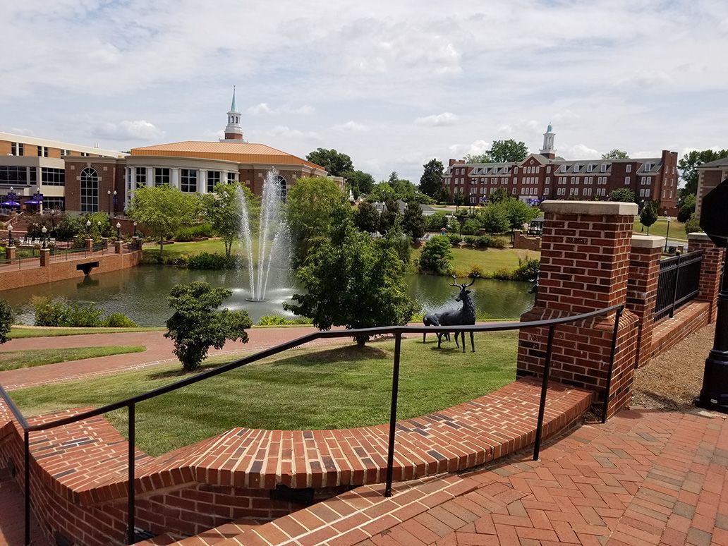 A brick walkway leading to a fountain in a park