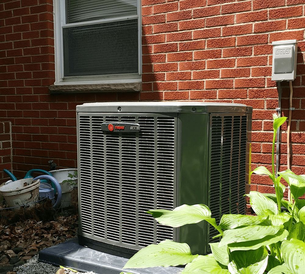An air conditioner is sitting on the side of a brick building.