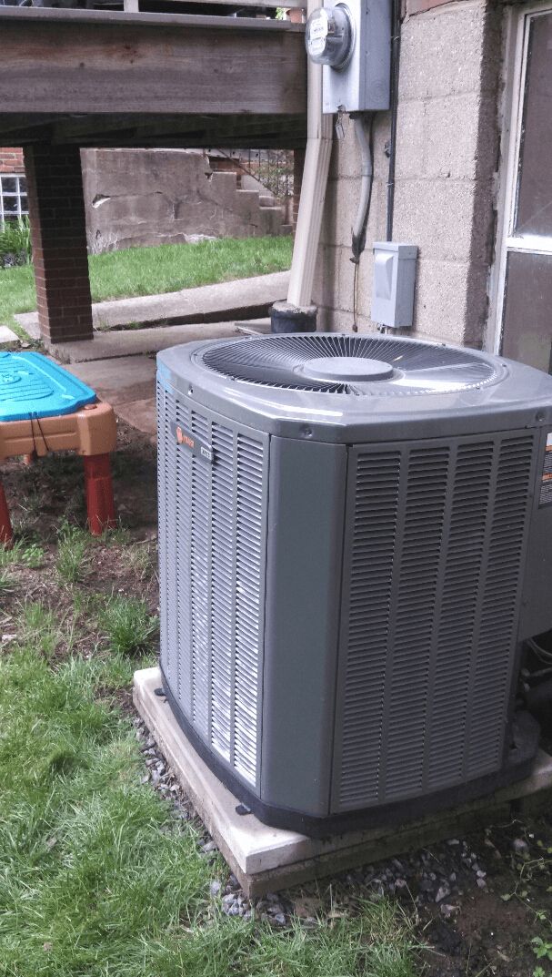 A large air conditioner is sitting on the side of a building.