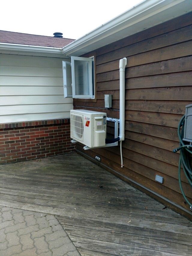 An air conditioner is mounted on the side of a house.