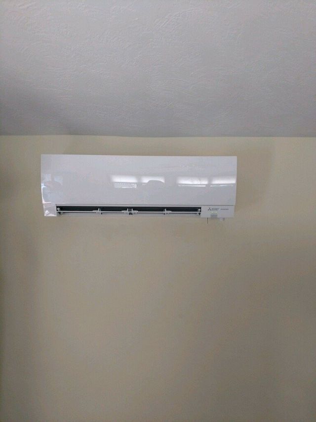 A white air conditioner is hanging on a wall in a room.