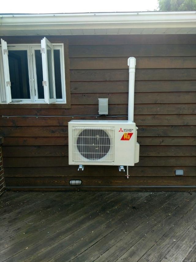 A mitsubishi air conditioner is mounted on the side of a house