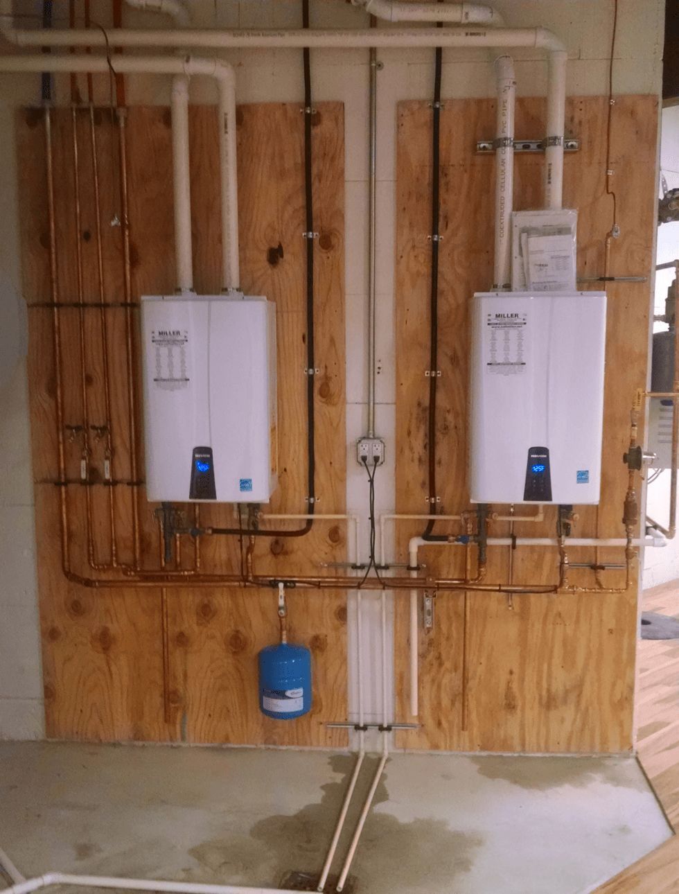 Two water heaters are mounted to a wooden wall