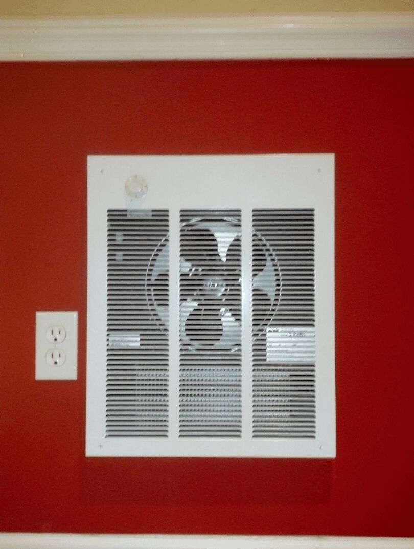 A white fan is mounted on a red wall