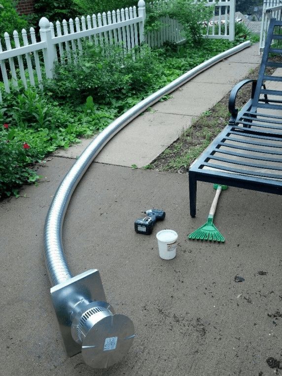 A hose is laying on the sidewalk next to a bench