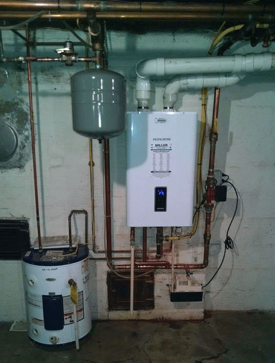 A water heater is sitting next to a boiler in a basement