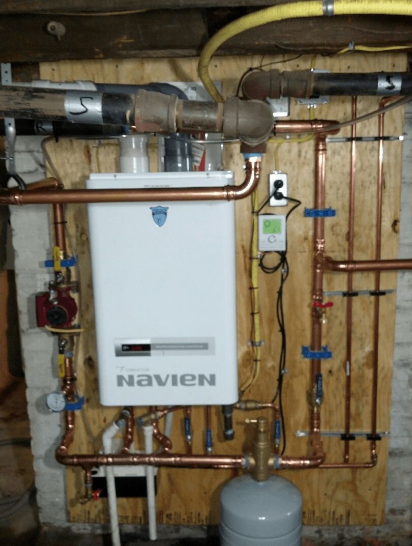 A white navien boiler is surrounded by copper pipes
