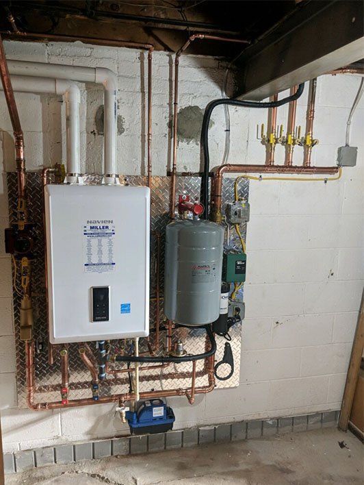 A water heater is installed in a basement with copper pipes.
