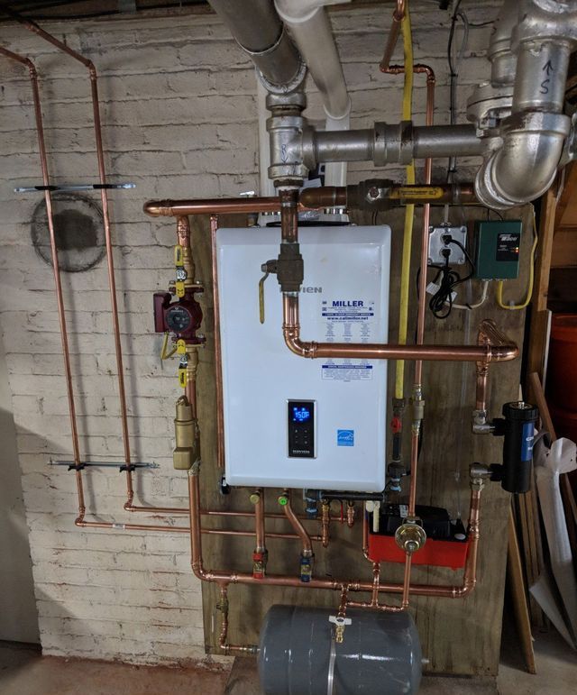 A white water heater is surrounded by copper pipes