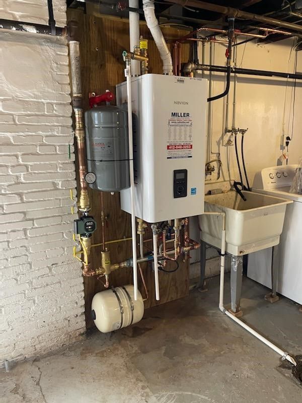 A water heater is installed in a basement next to a laundry sink.