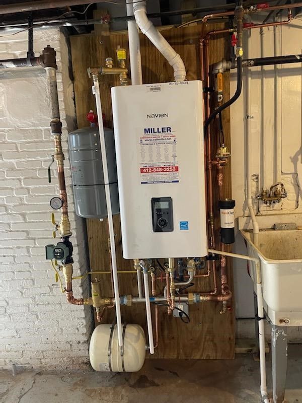 A white water heater is hanging on a wall next to a sink.