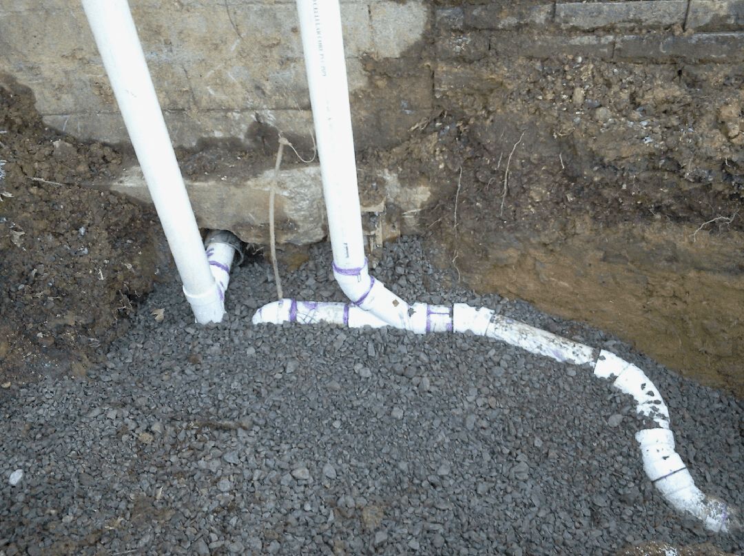 A drain pipe is being installed in a hole in the ground.