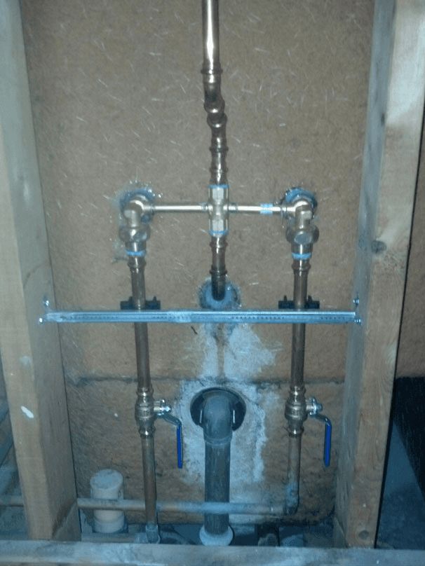 A bathroom with copper pipes and blue handles