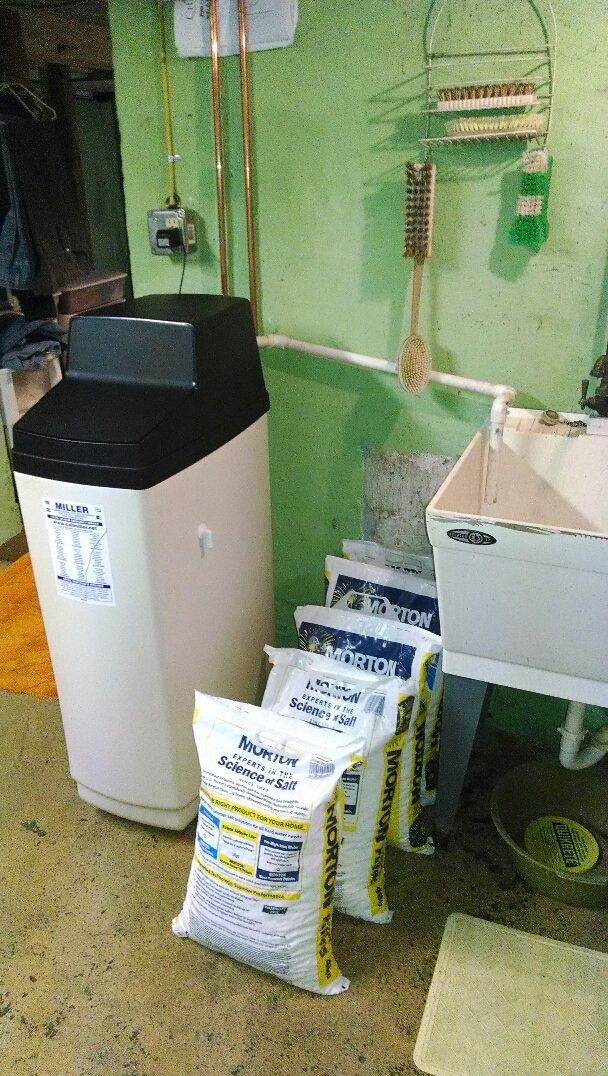 A water softener is sitting next to a sink in a laundry room.