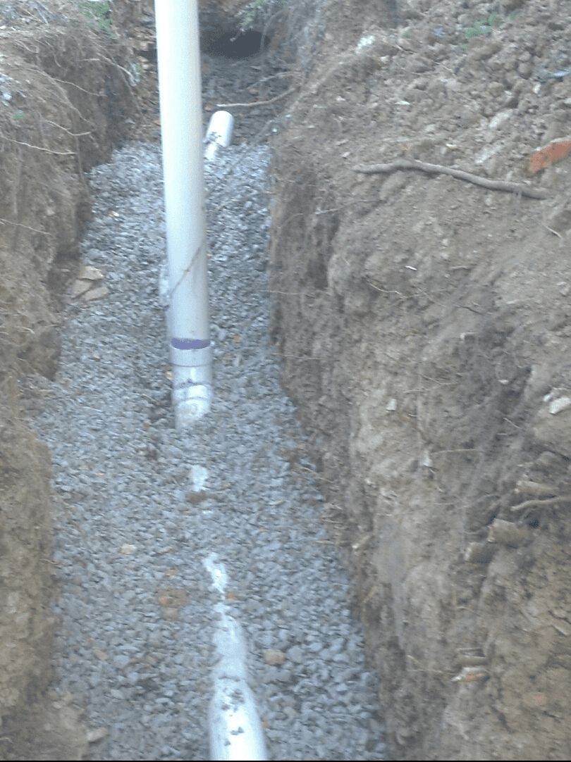 A drain pipe is being installed in a trench.
