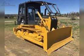 A yellow bulldozer is parked in a dirt field.