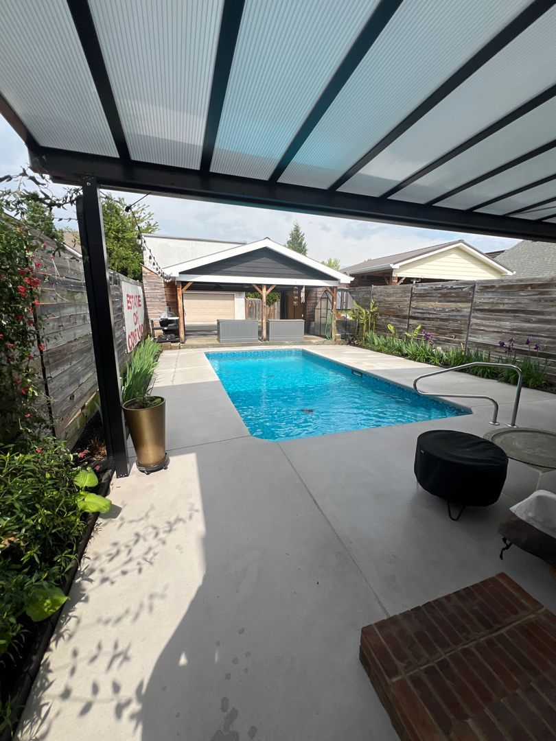 There is a large swimming pool in the backyard of a house.