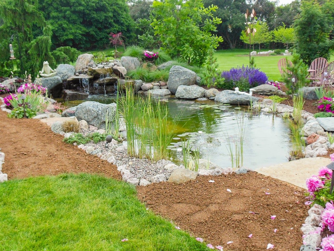 There is a pond in the middle of the garden with a waterfall.