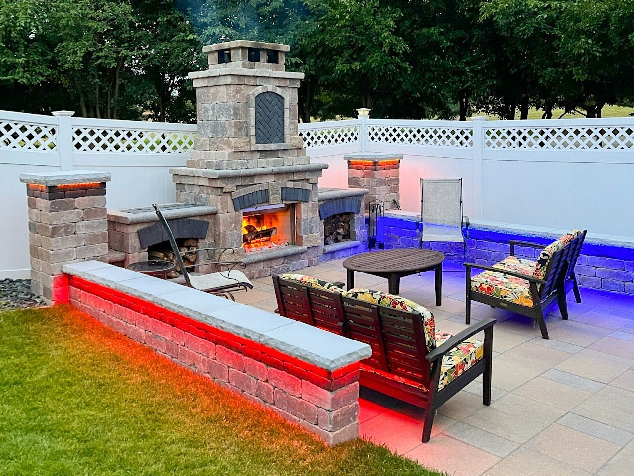 A patio with a fireplace, couch, chairs and a table.